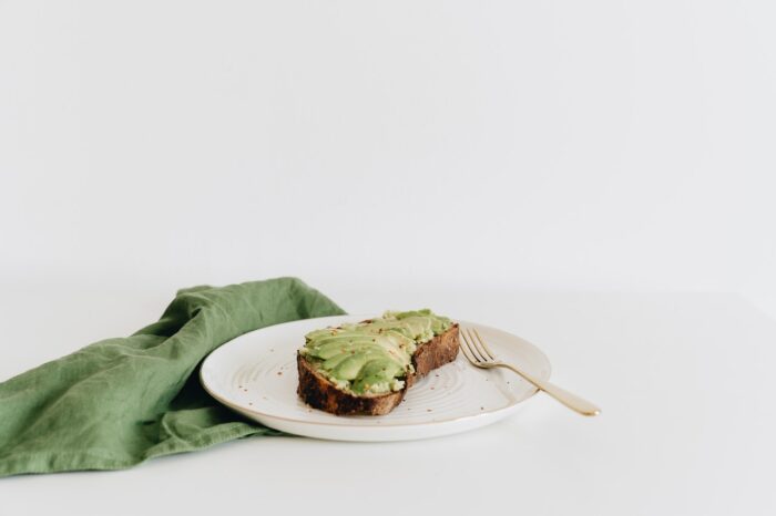 Avocado toast on a white plate with a green napkin.